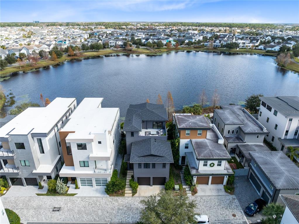 An aerial view shows several modern multi-story houses situated along the edge of a lake — 8351 EDELMAN LANE, ORLANDO, FL