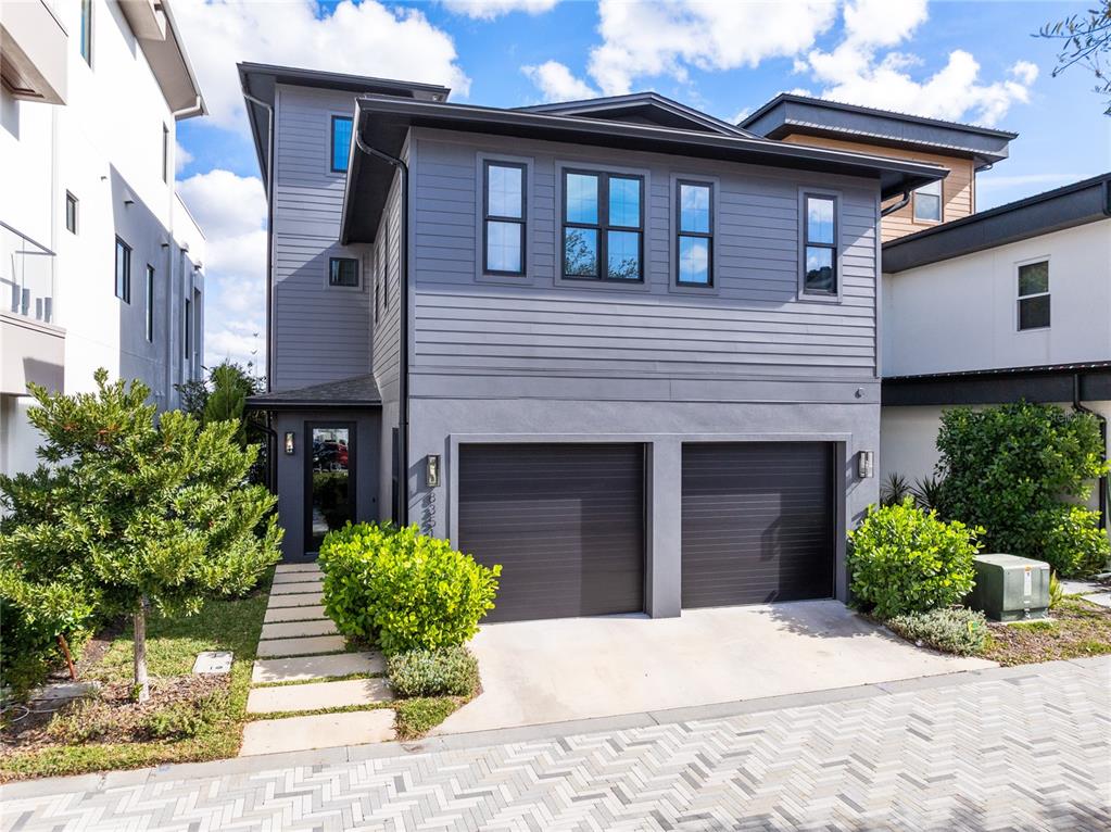 A two-story gray house features a two-car garage and a paved walkway — 8351 EDELMAN LANE, ORLANDO, FL