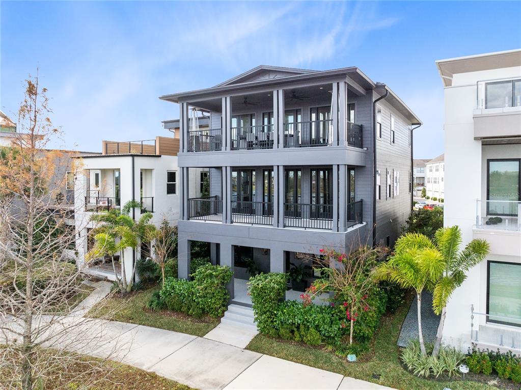 A three-story gray house with balconies and a ground-level entrance surrounded by landscaping — 8351 EDELMAN LANE, ORLANDO, FL