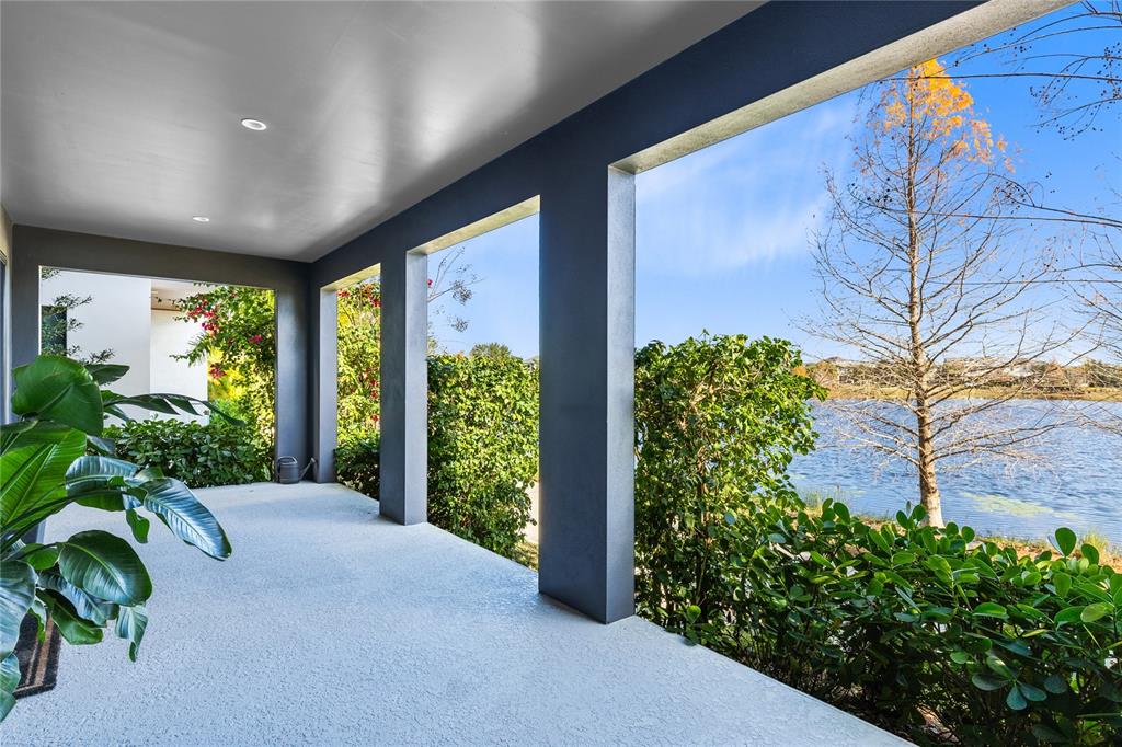 A covered patio with gray pillars overlooks a lake and trees on a sunny day — 8351 EDELMAN LANE, ORLANDO, FL