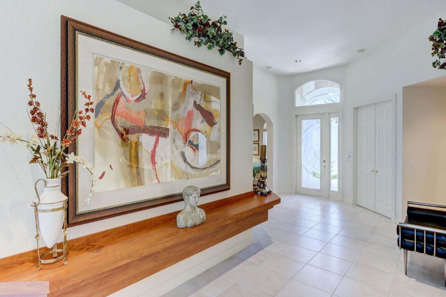 A bright entryway features a long wooden floating shelf, abstract wall art, and tiled floors — 6255 NW 42nd Way, Boca Raton FL 33496, BOCA RATON, FL