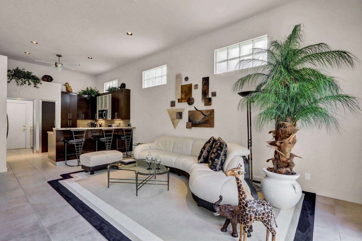 A living room features a curved white sofa, a glass coffee table, and a kitchen bar — 6255 NW 42nd Way, Boca Raton FL 33496, BOCA RATON, FL