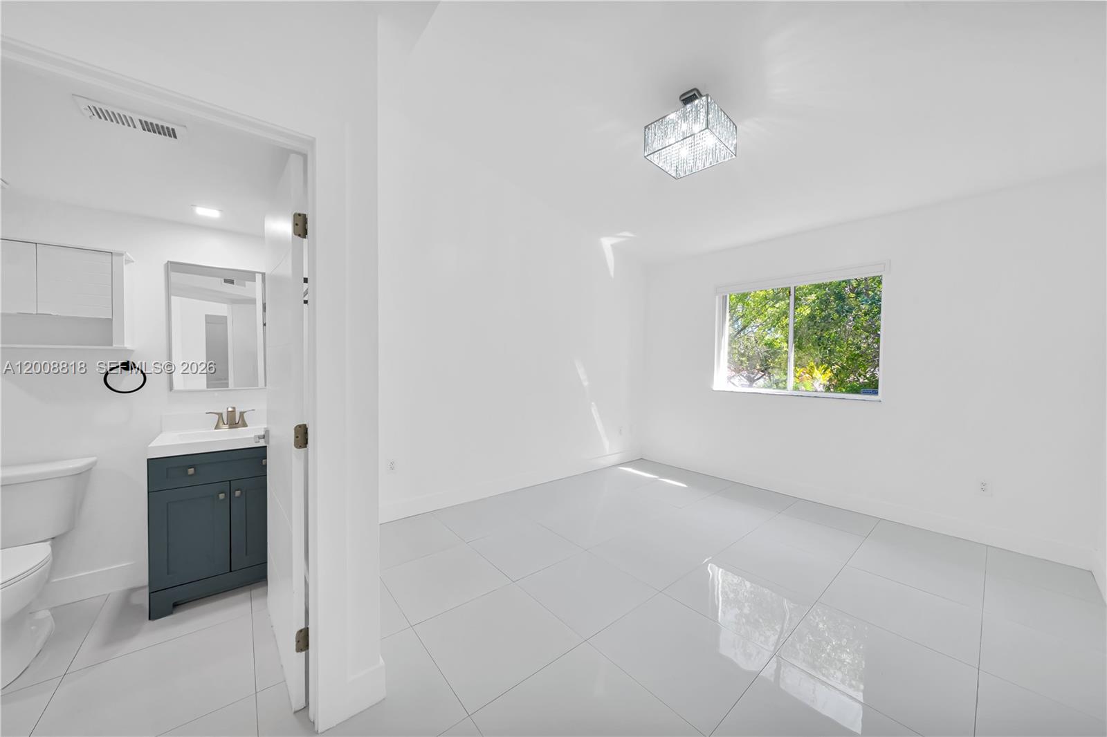 A bright room with white walls, large floor tiles, and an attached small bathroom — 13170 SW 66 Ter # 1810B, Miami FL 33183, MIAMI, FL