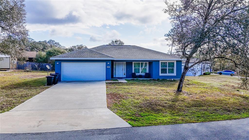 A blue single-story house with a two-car garage and a concrete driveway — 16417 SW 27TH CIRCLE, OCALA, FL