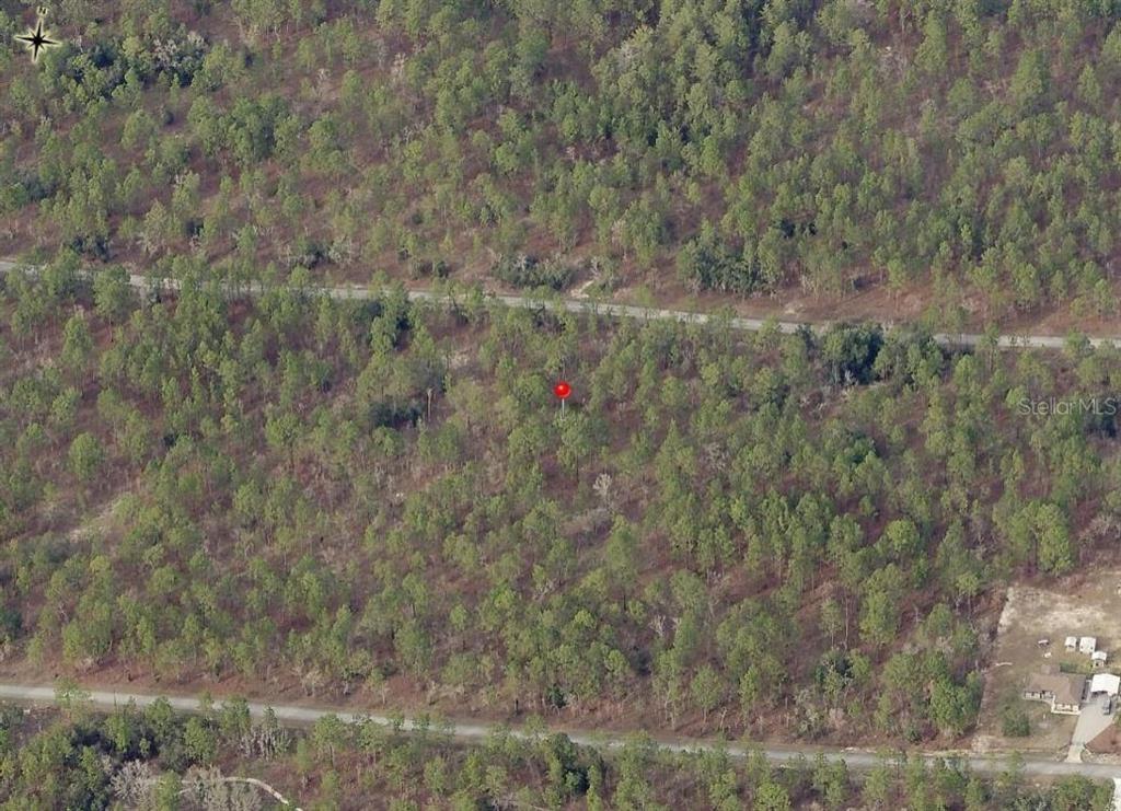 An aerial view shows a wooded lot with a red marker between two paved roads — Lot 7 NW HEMLOCK AVENUE, DUNNELLON, FL
