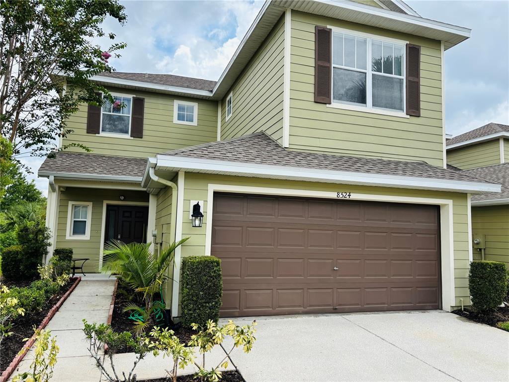 A two-story house with light green siding, a brown garage door, and a concrete driveway — 8524 SANDPIPER RIDGE AVENUE, TAMPA, FL