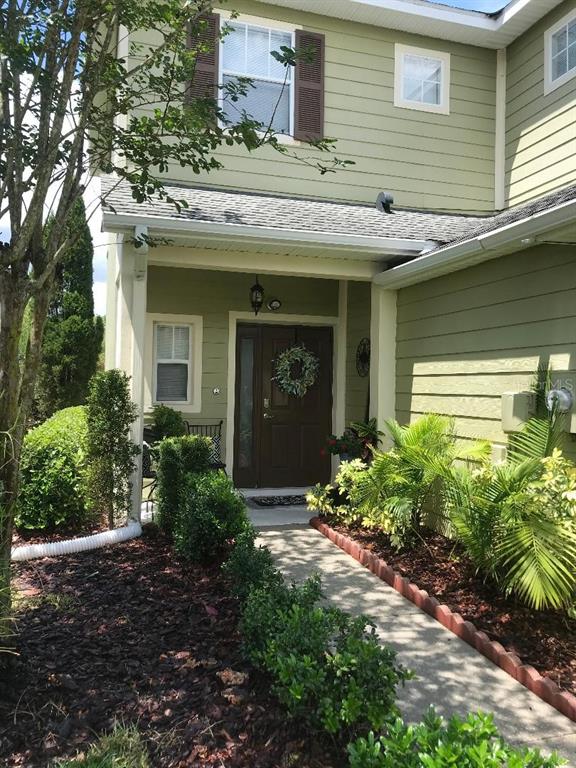 The exterior of a two-story house features light green siding, a front porch, and landscaping — 8524 SANDPIPER RIDGE AVENUE, TAMPA, FL