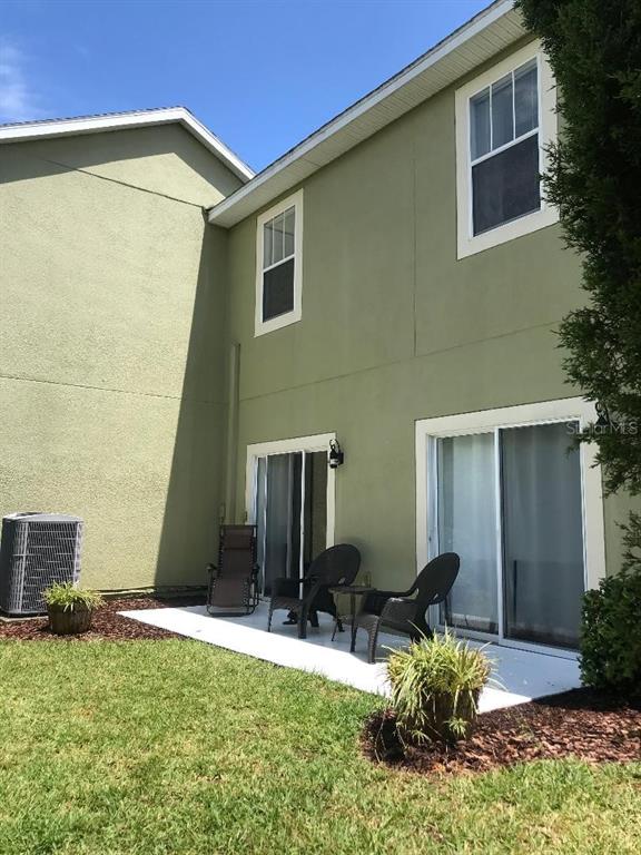 The exterior of a two-story house features a concrete patio, sliding glass doors, and lawn — 8524 SANDPIPER RIDGE AVENUE, TAMPA, FL