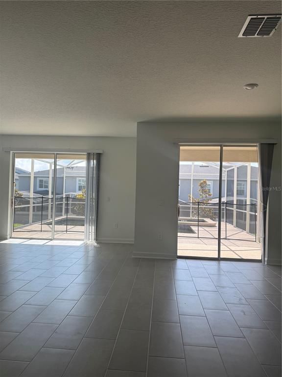 A room with light-colored tile flooring and two sliding glass doors leading to a screened patio — 1123 KINGSBARN STREET, DAVENPORT, FL