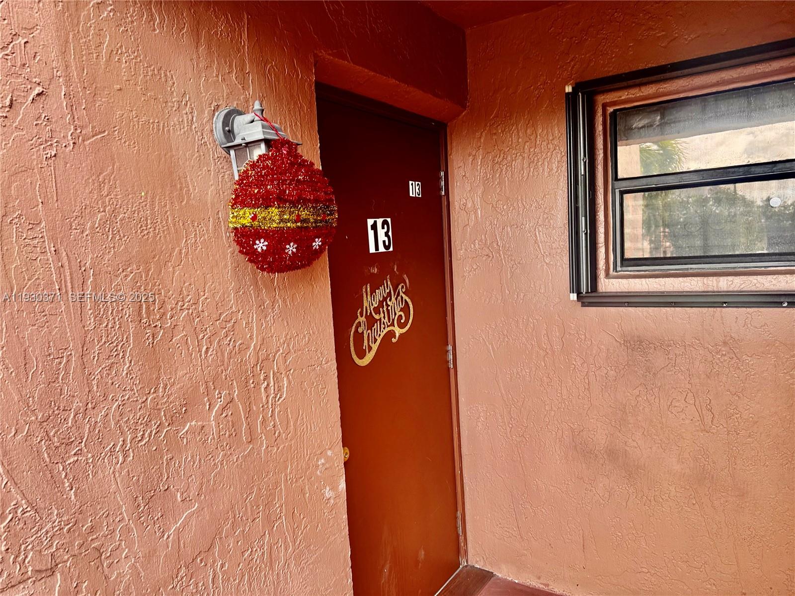 A brown door marked with the number 13 features a festive ornament and holiday decal — 6455 W 27th Ave # 13, Hialeah FL 33016, HIALEAH, FL