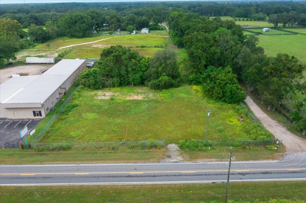 An aerial view shows a vacant, fenced rectangular lot adjacent to a commercial building — 16262 S HIGHWAY 475, SUMMERFIELD, FL