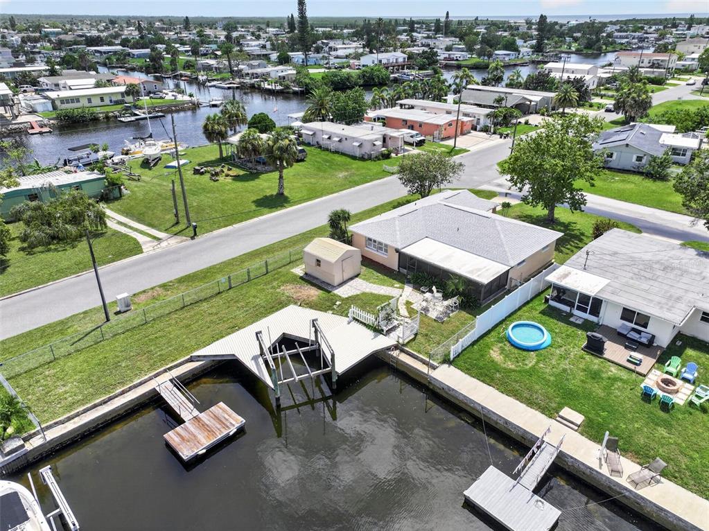 An aerial view shows a waterfront house with a boat lift, dock, and backyard pool — 13224 NEPTUNE DRIVE, HUDSON, FL