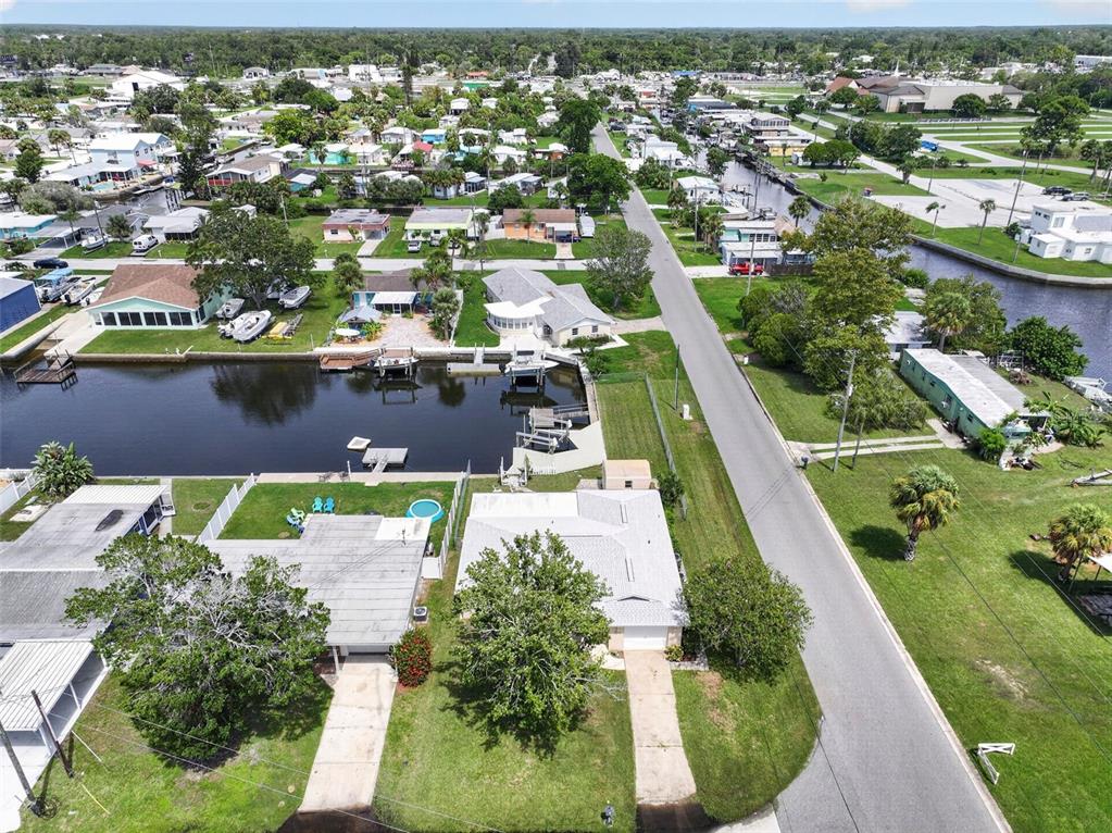 An aerial view shows a residential neighborhood with houses, a canal, and a paved road — 13224 NEPTUNE DRIVE, HUDSON, FL