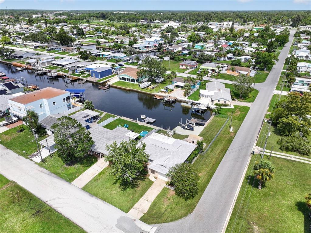 An aerial view shows a residential neighborhood with houses along a canal and a road — 13224 NEPTUNE DRIVE, HUDSON, FL