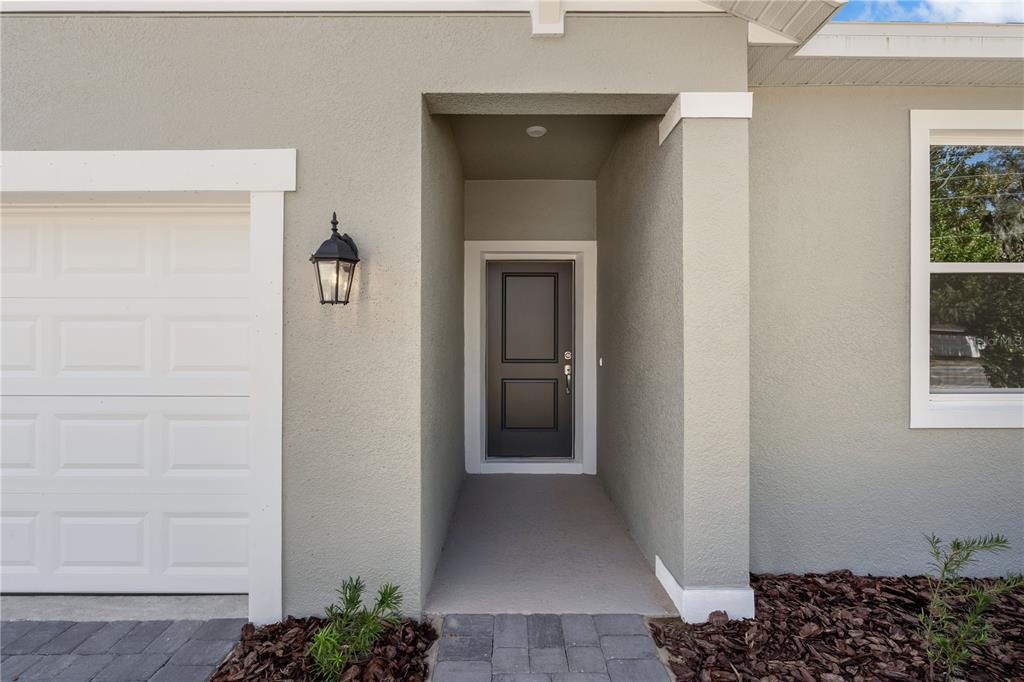 The exterior of a house features a dark front door, a garage, and a walkway — 10173 HUNTINGNET WAY, LEESBURG, FL