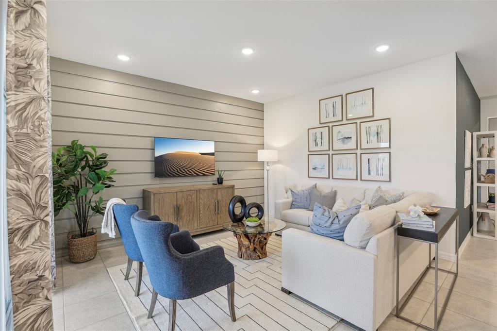 A living room features a shiplap accent wall, a television, blue armchairs, and a sofa — 10173 HUNTINGNET WAY, LEESBURG, FL
