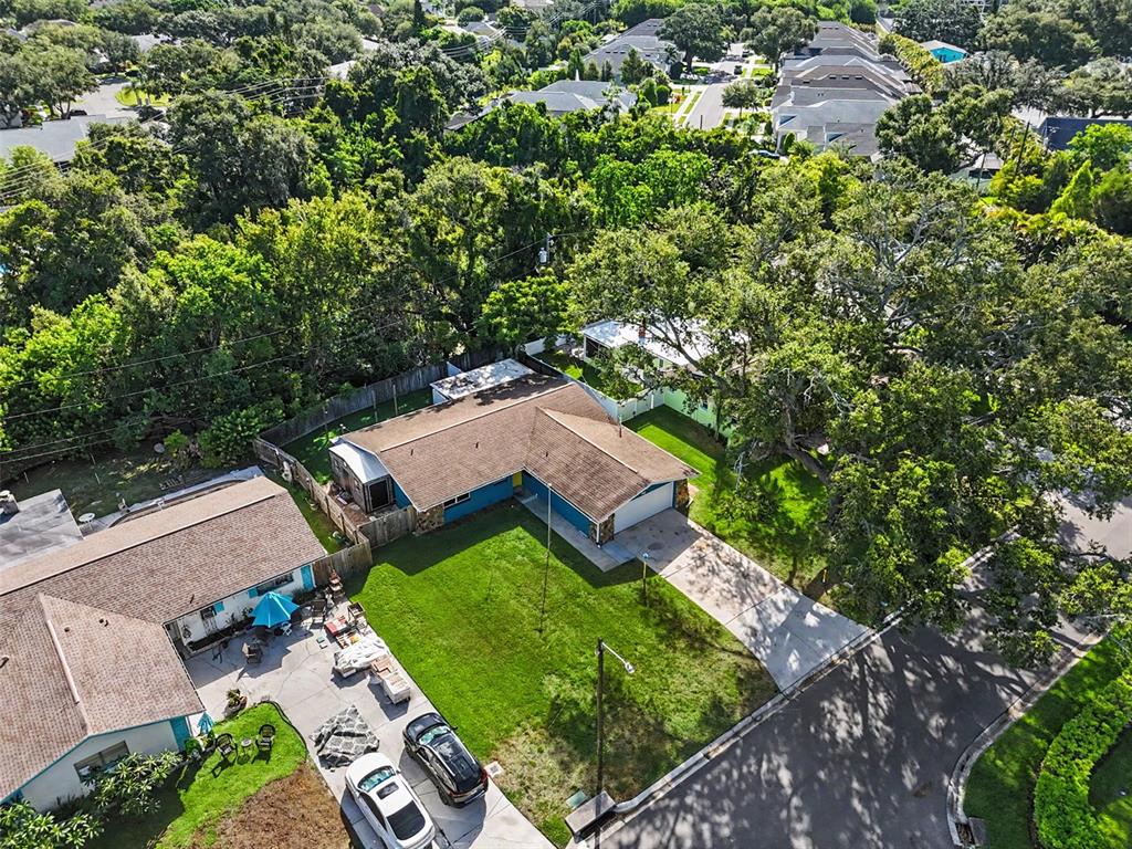 An aerial view shows a blue ranch-style house with a brown roof and a driveway — 986 LEXINGTON DRIVE, DUNEDIN, FL