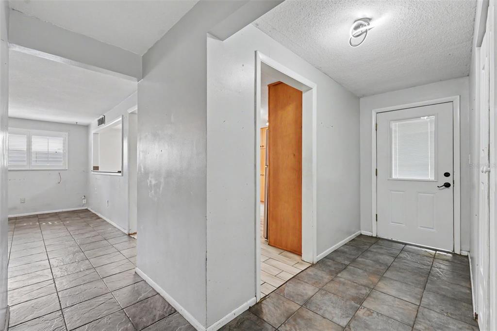A kitchen features light wood cabinets, a dark kitchen island, and gray tile flooring — 986 LEXINGTON DRIVE, DUNEDIN, FL