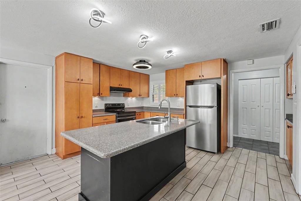 A kitchen with wood cabinets, granite countertops, stainless steel appliances, and a central island — 986 LEXINGTON DRIVE, DUNEDIN, FL