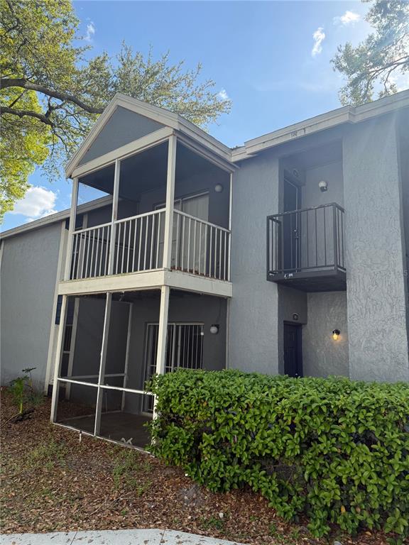 A two-story apartment building exterior features a screened-in balcony and a small metal balcony — 3827 BAY CLUB CIRCLE UNIT 103, KISSIMMEE, FL