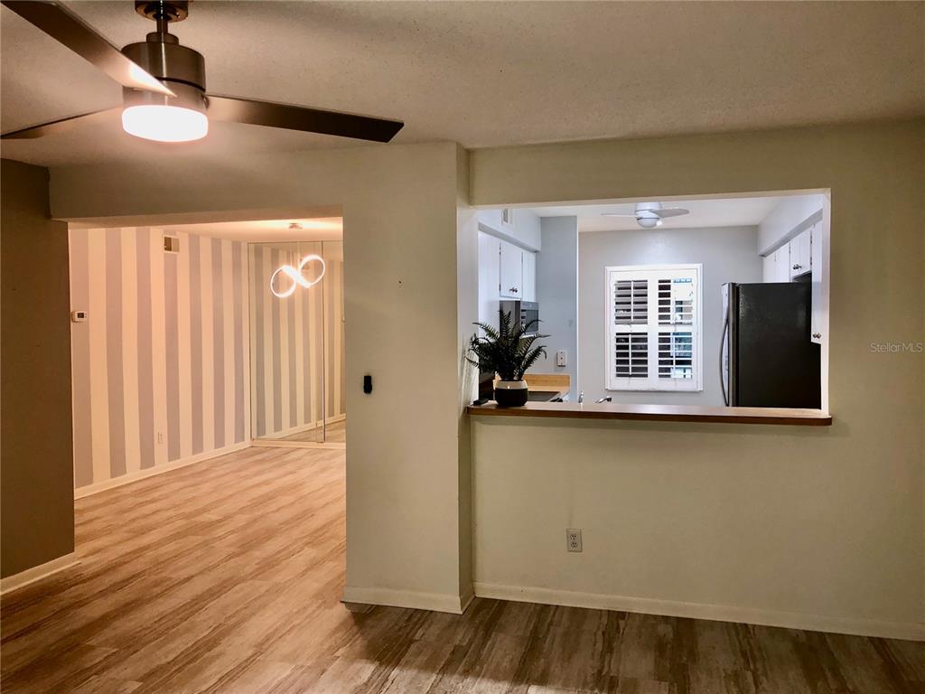 A view from a living area looking into a kitchen with a breakfast bar — 3399 MERMOOR DRIVE UNIT 206, PALM HARBOR, FL