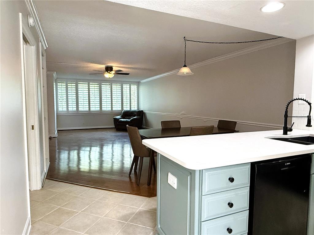 A kitchen island with light blue cabinets overlooks a dining area and living room — 2614 COVE CAY DRIVE UNIT 204, CLEARWATER, FL