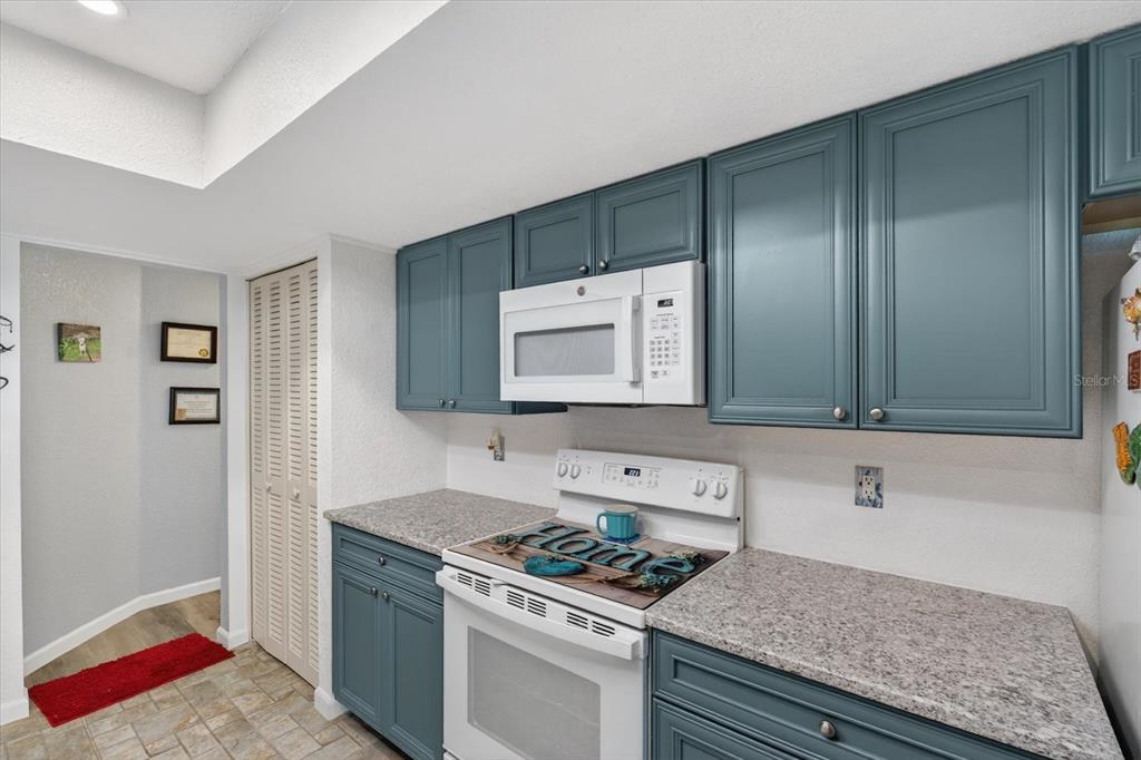 A kitchen features blue cabinets, white appliances, and speckled granite countertops — 4075 DRANCE STREET, PUNTA GORDA, FL