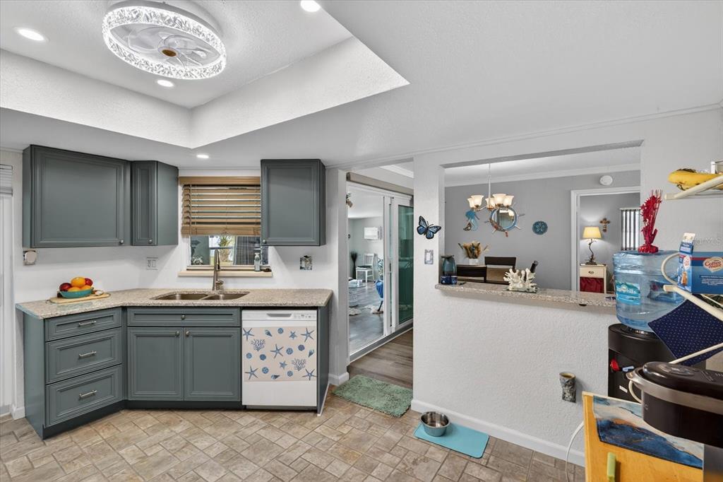 A kitchen with gray cabinets, granite countertops, and a pass-through window to the dining area — 4075 DRANCE STREET, PUNTA GORDA, FL