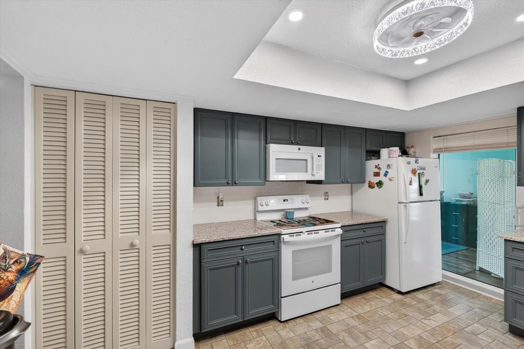A kitchen features dark gray cabinets, white appliances, granite countertops, and light-colored louvered closet doors — 4075 DRANCE STREET, PUNTA GORDA, FL
