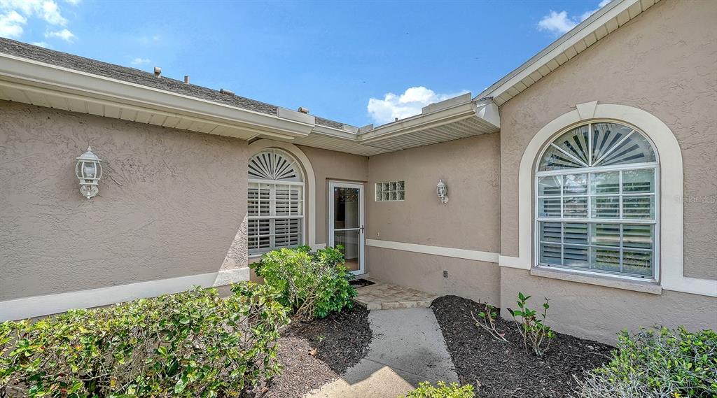 The exterior of a beige stucco house features a front entryway with arched windows — 5126 BLUE ASH AVENUE, SARASOTA, FL