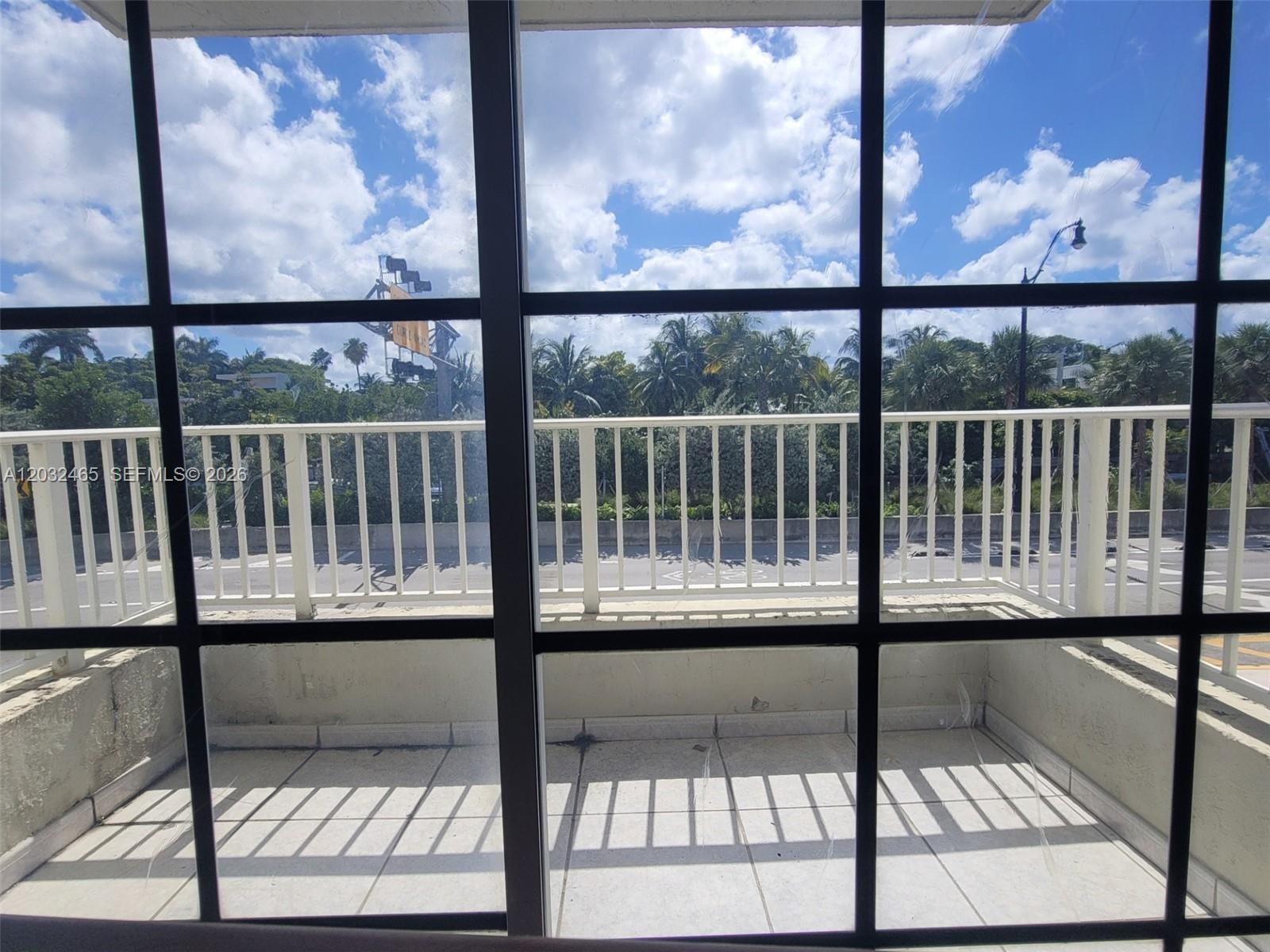 A balcony with a white railing is viewed through a large grid-patterned window — 2600 Collins Ave # 201, Miami Beach FL 33140, MIAMI BEACH, FL