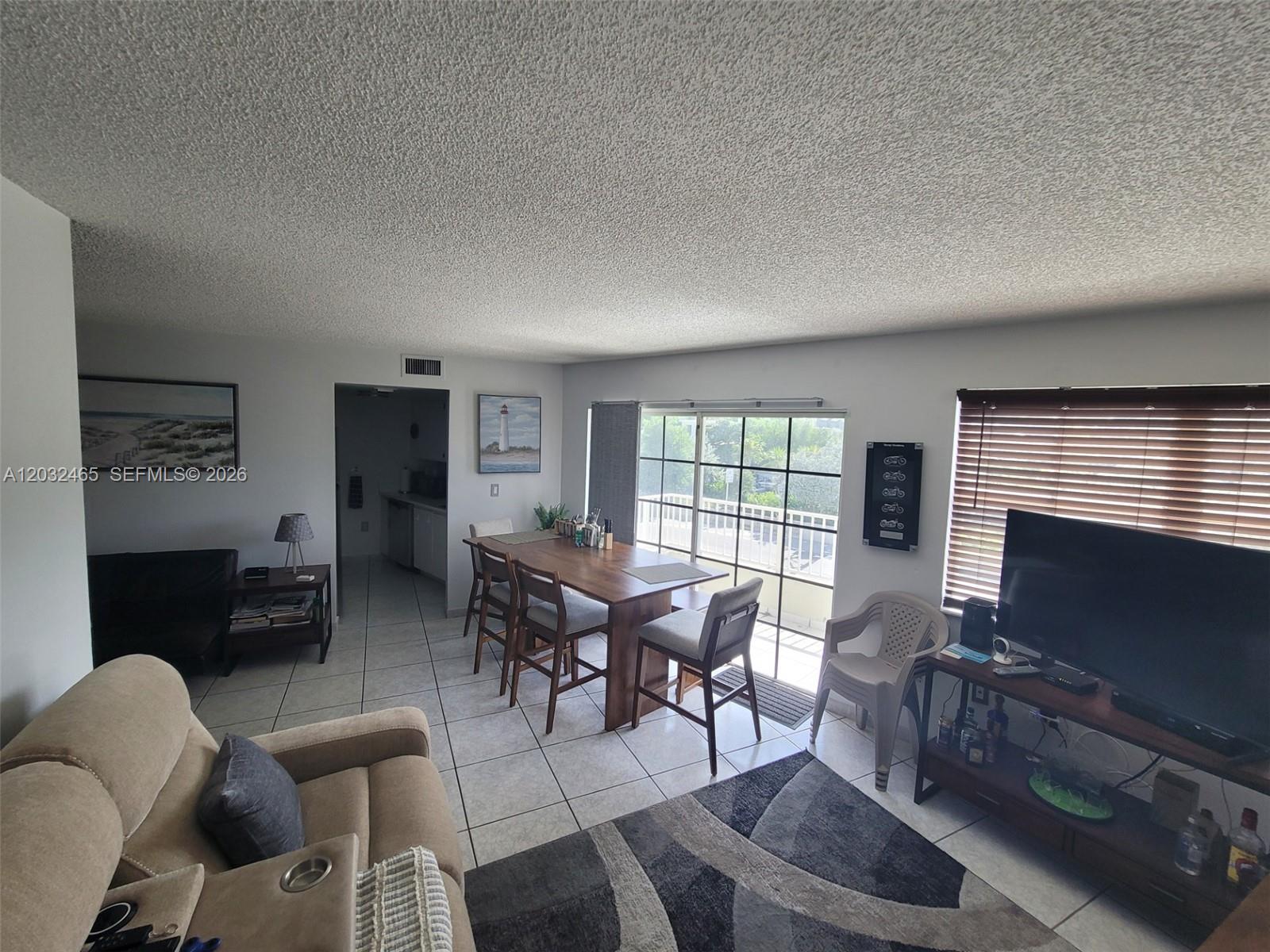 A living and dining area features tile floors, a wooden table, and a sliding glass door — 2600 Collins Ave # 201, Miami Beach FL 33140, MIAMI BEACH, FL