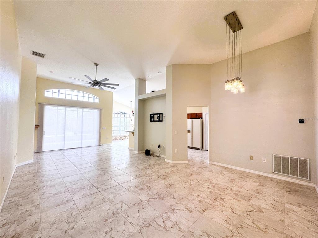 A spacious living area features high ceilings, tile flooring, a ceiling fan, and pendant lighting — 140 MOSS LANE, DAVENPORT, FL