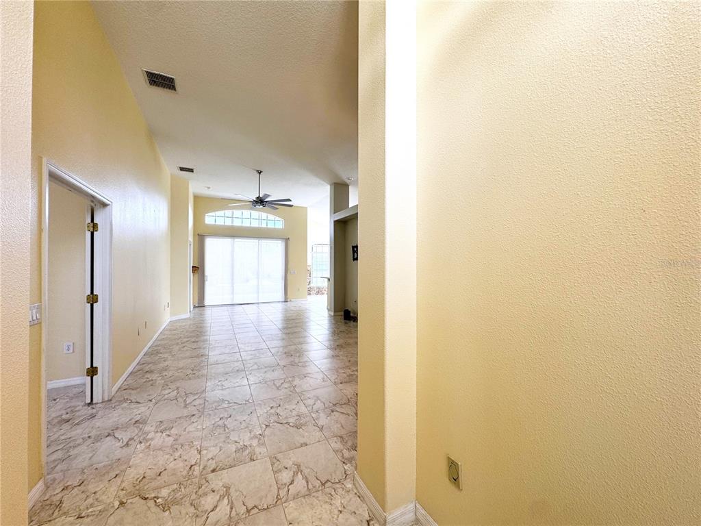 A view from a hallway looking into a living area with tile floors and vaulted ceilings — 140 MOSS LANE, DAVENPORT, FL