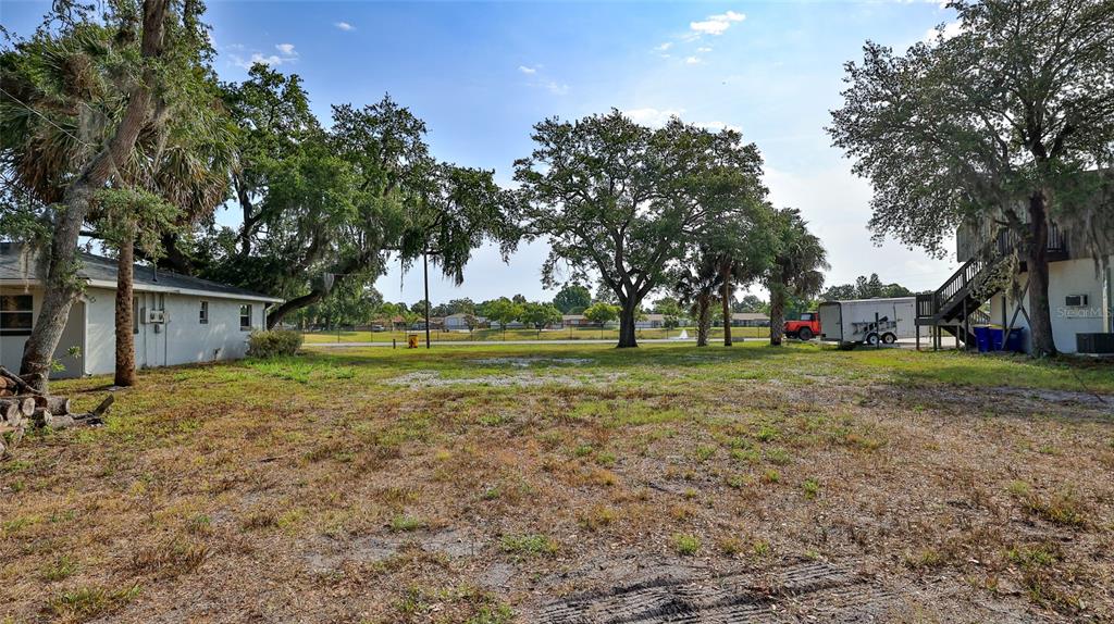 A vacant, grassy lot sits between two buildings under a bright, sunny sky — 1802 N FERN PALM DRIVE, EDGEWATER, FL