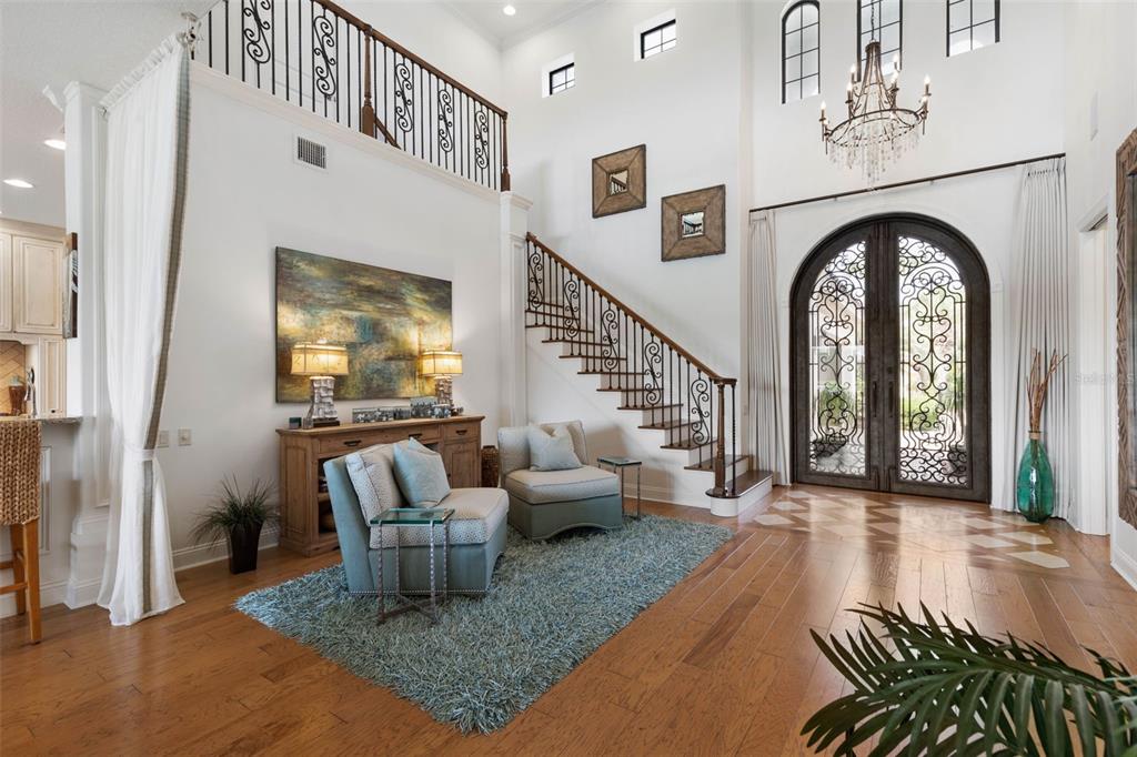 A grand foyer features a staircase, arched iron doors, hardwood floors, and a seating area — 34 KINGFISHER LANE, PALM COAST, FL