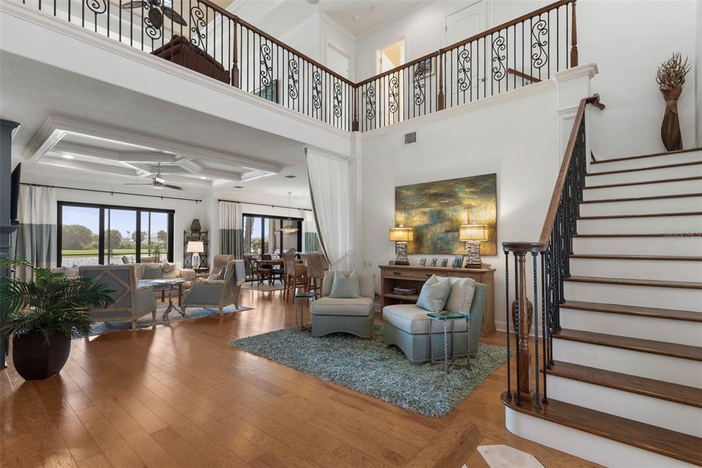 A spacious living room with hardwood floors, a staircase, and a two-story open balcony — 34 KINGFISHER LANE, PALM COAST, FL