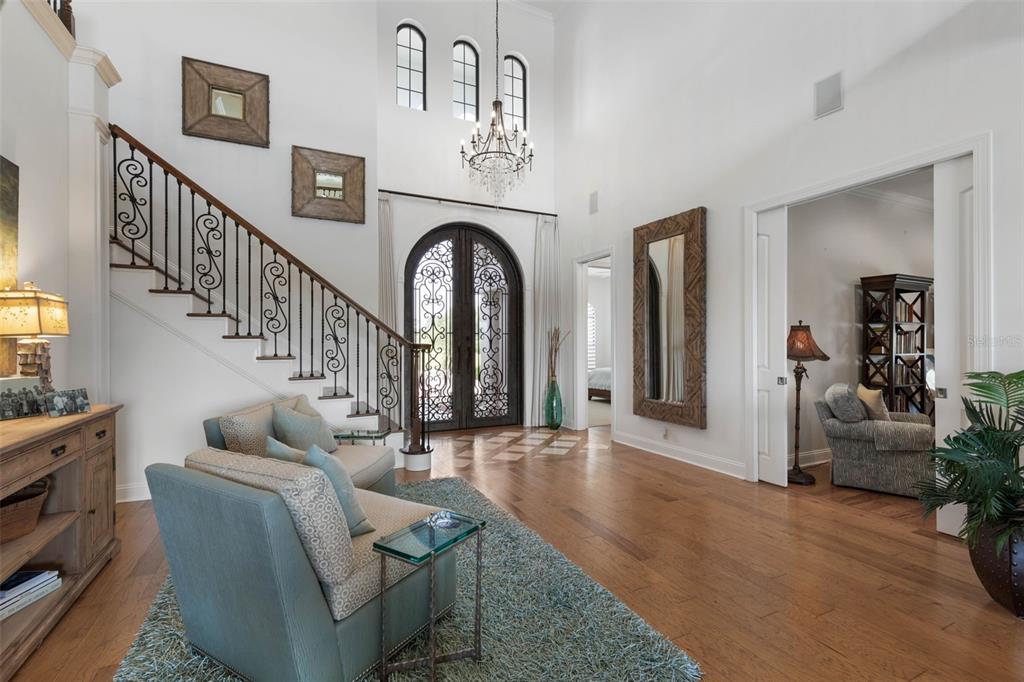 A bright foyer features a grand staircase, arched double doors, and a chandelier — 34 KINGFISHER LANE, PALM COAST, FL