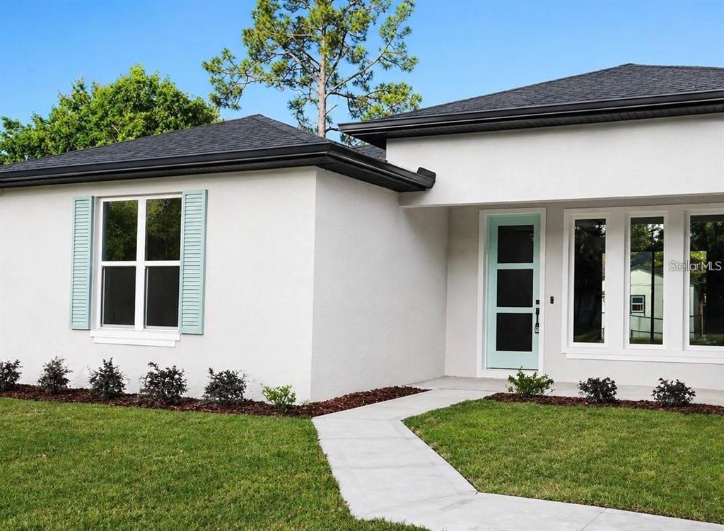 A white stucco house exterior features a light blue front door and matching window shutters — 14 POWDER HILL LANE, PALM COAST, FL