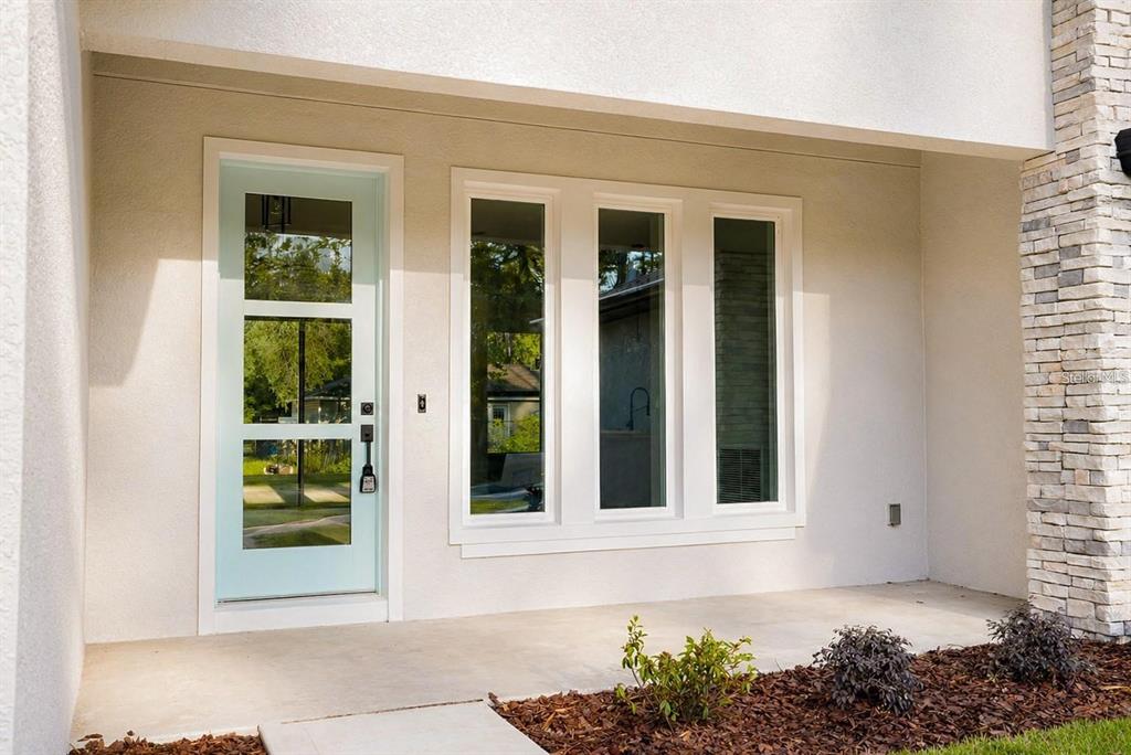 A light blue front door sits beside three tall windows on a covered concrete porch — 14 POWDER HILL LANE, PALM COAST, FL