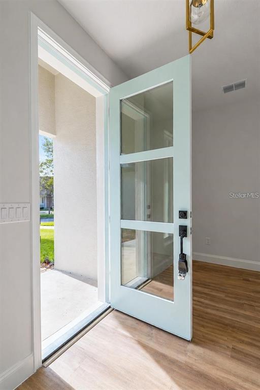 A light blue front door with three glass panels opens into a room with wood flooring — 14 POWDER HILL LANE, PALM COAST, FL