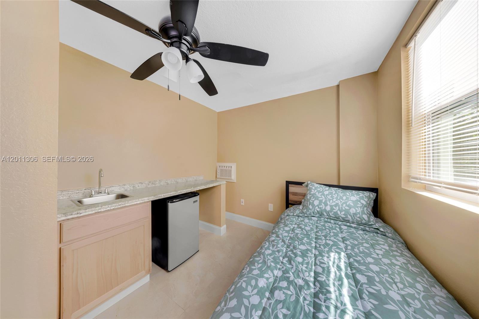 A small bedroom features a single bed, a kitchenette with a sink, and a ceiling fan — 193 NW 58th St, Miami FL 33127, MIAMI, FL