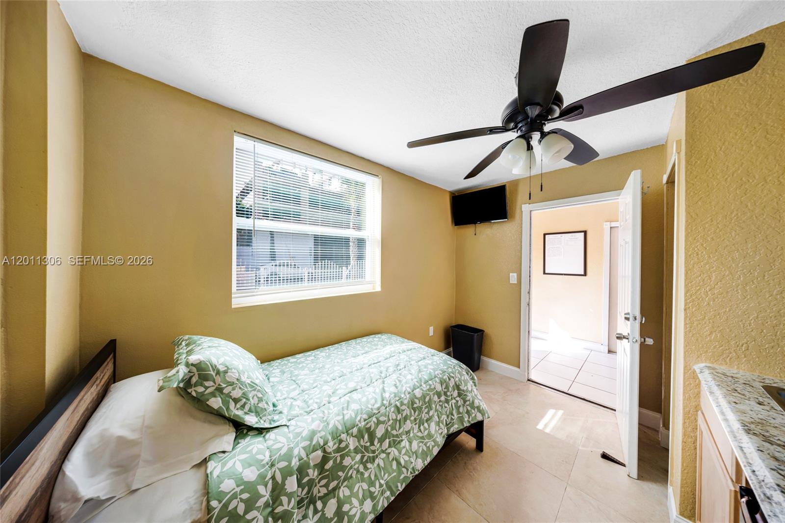A bedroom features a single bed, a ceiling fan, and a doorway leading outside — 193 NW 58th St, Miami FL 33127, MIAMI, FL