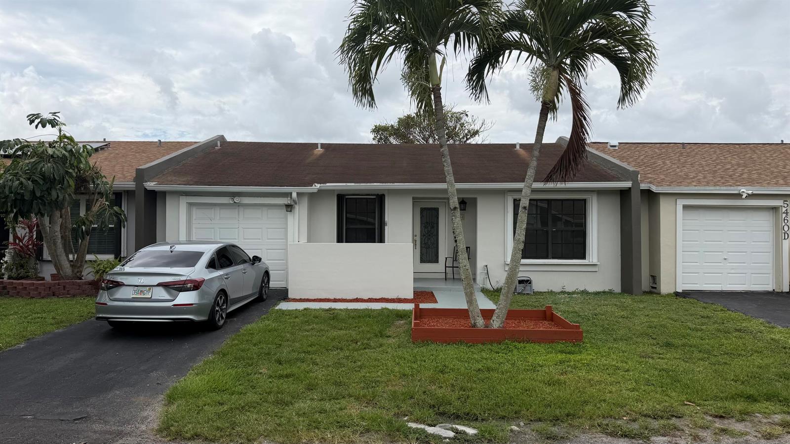 A single-story townhouse with a silver sedan parked in the driveway and two palm trees — 5460 S Lakewood Cir S # C, Margate FL 33063, MARGATE, FL