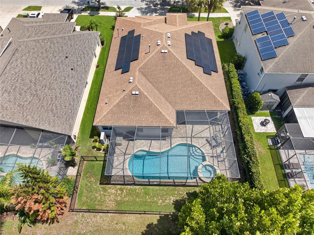 An aerial view shows a house with solar panels, a screened-in pool, and a backyard — 15601 STARLING WATER DRIVE, LITHIA, FL