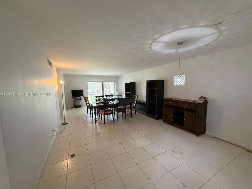 A dining area with tile flooring, a dark wood table, and a matching sideboard — 3280 Spanish Moss Ter # 110, Lauderhill FL 33319, LAUDERHILL, FL