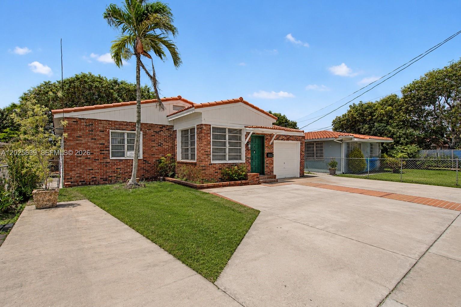 A single-story brick house with a tile roof, a palm tree, and a concrete driveway — MIAMI, FL