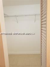 A small walk-in closet with white walls, a single hanging rod, and light-colored tile flooring — 620 NE 12th Ave # 408, Hallandale Beach FL 33009, HALLANDALE BEACH, FL