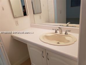 A bathroom vanity with a white countertop, a single sink, and a large wall mirror — 620 NE 12th Ave # 408, Hallandale Beach FL 33009, HALLANDALE BEACH, FL