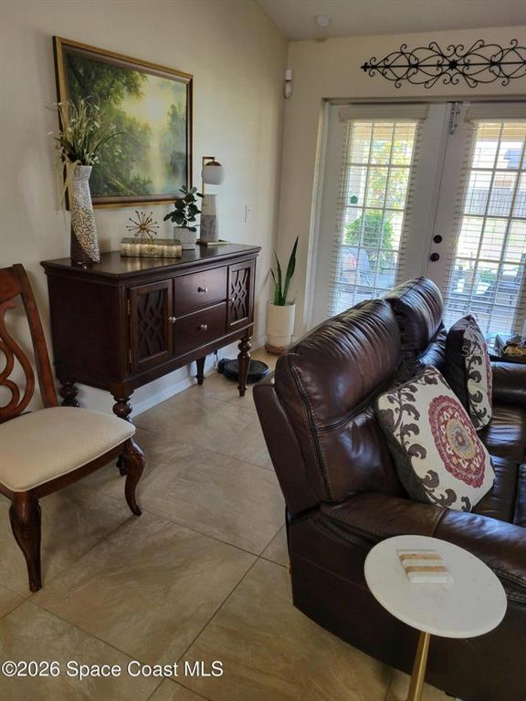 A living room features a dark wood sideboard, a leather sofa, and tile flooring — 1703 VALCOURT STREET NW, PALM BAY, FL